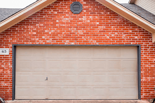 A two-car garage door set into a red brick wall, with the steel lintel spanning the opening above it